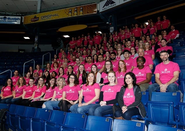 Stadium of 100 plus Skyline Employees wearing pink shirts