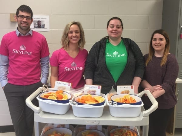 Four Skyline staff in front of food they prepared for the Month of Giving