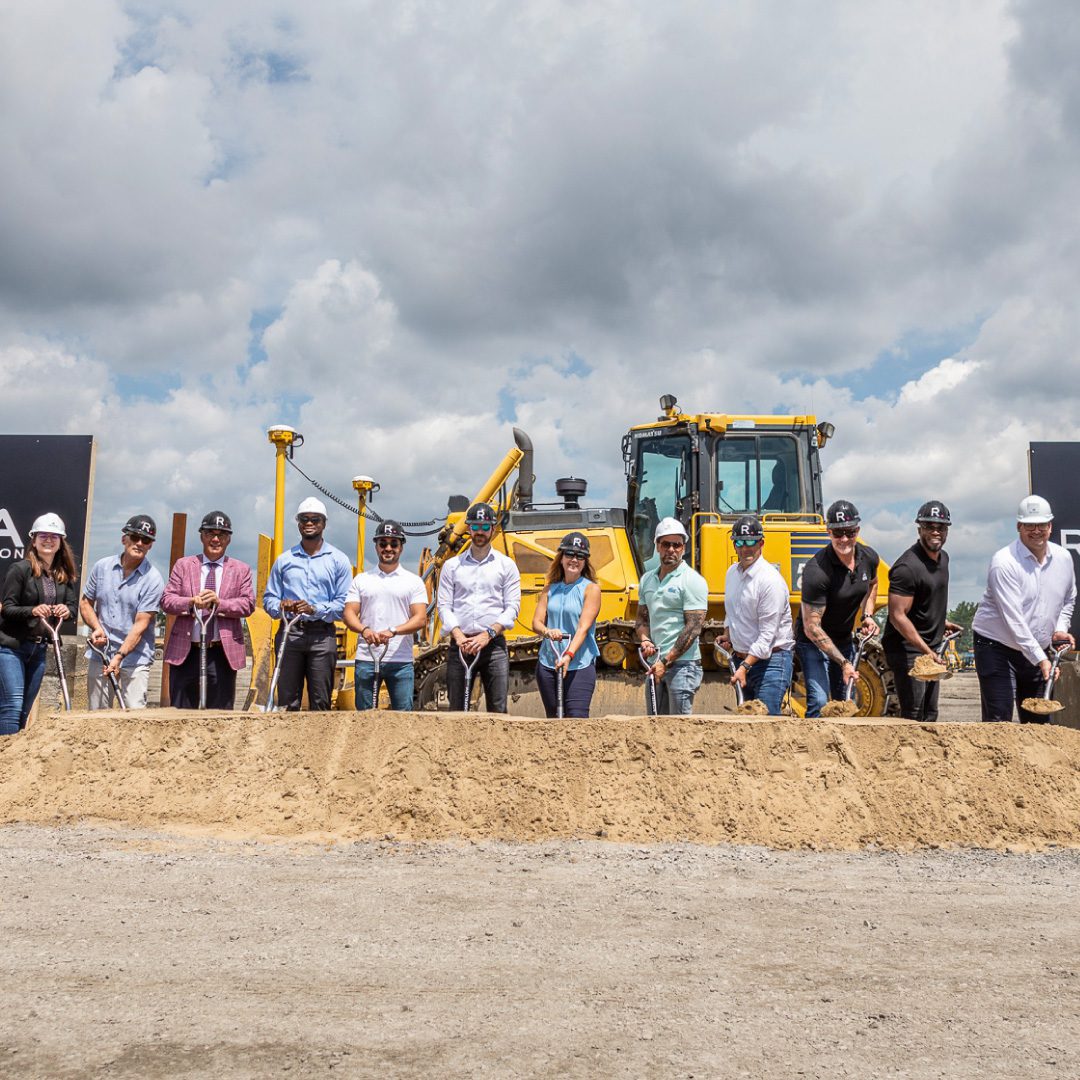 Groundbreaking photo with team standing with shovels in front of a pile of dirt