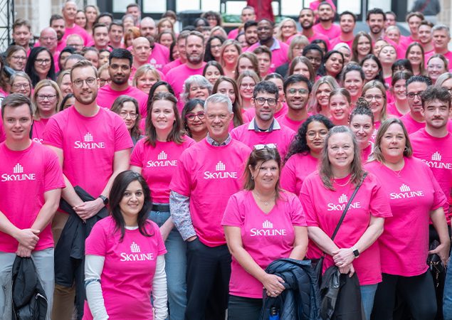 A group of smiling employees in bright pink t-shirts