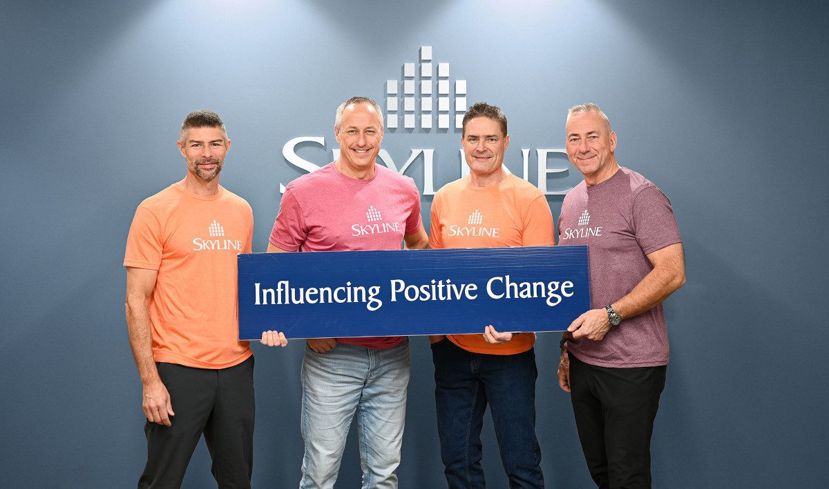 Skyline's founders holding a sign reading Influencing Positive Change