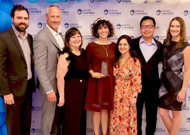 Skyline employees at an award gala, smiling and posing with an award trophy.