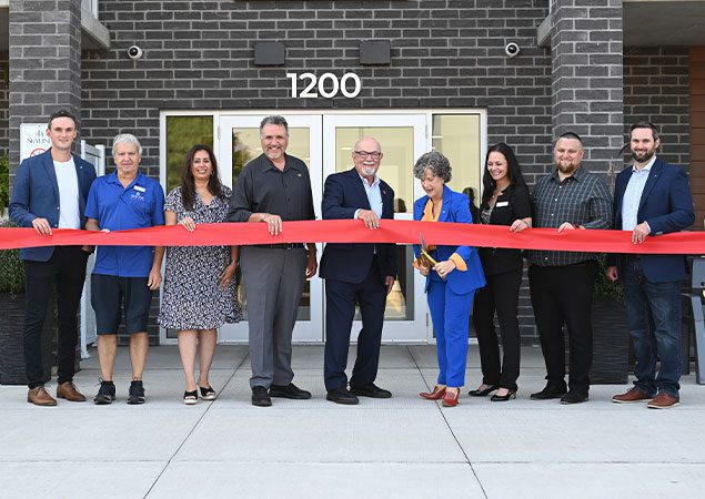 Skyline staff and dignitaries cut the ribbon on a new apartment building.